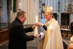 Kapelaan Harold van Overbeek neemt namens de parochie de kaars in ontvangst van Mgr. De Korte